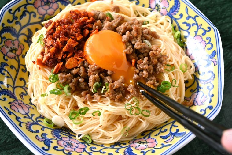 混ぜそうめんのトッピングの卵黄を箸で割る様子