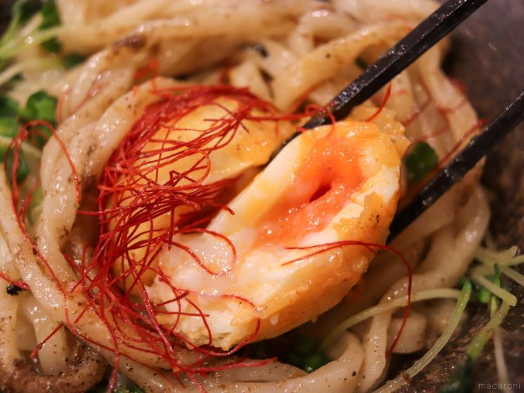 山下本気うどんの新メニュー元祖 油うどんの半熟卵天を箸で割っている様子