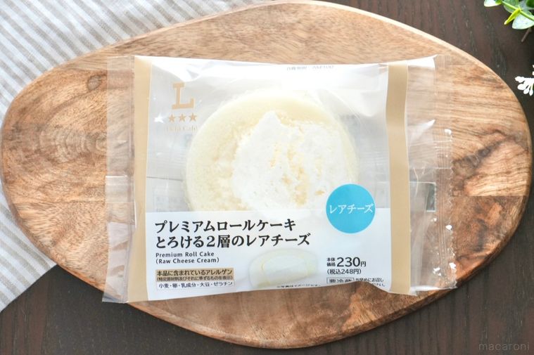 木のカッティングボードにのった白いレアチーズの丸いロールケーキとストライプの布とグリーン