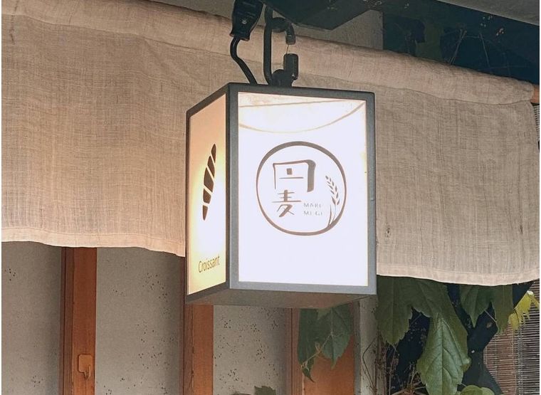 円麦の店先に掲げられた、クロワッサンのイラストと店名ロゴが入った四角い照明看板