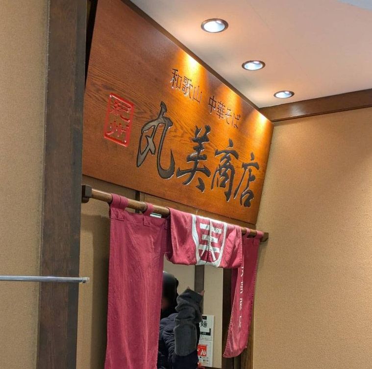 木の看板やえんじ色ののれんがかかった和歌山中華そば 丸美商店の外観