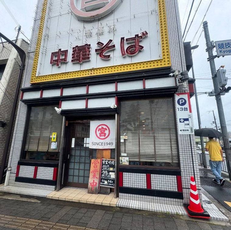 黄色い枠の白い大きな看板がかかった元車庫前丸宮中華そば 本店の外観