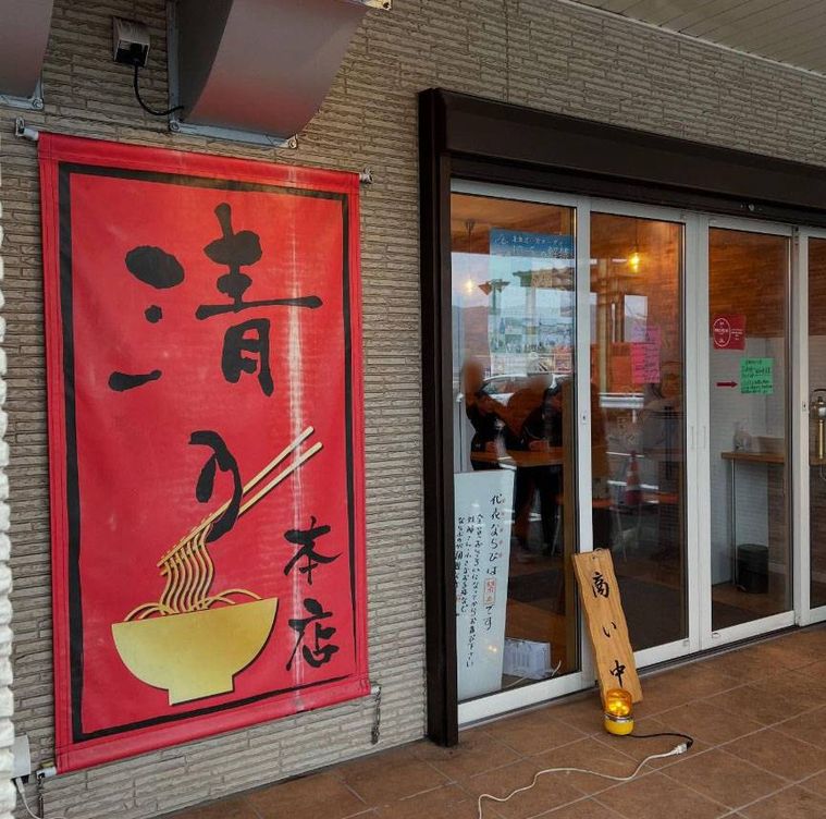 赤い店頭幕とガラス張りの入り口のある和 ダイニング 清乃 本店の外観