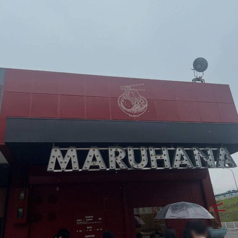 赤と黒の外壁に店名のアルファベット文字がかかったラーメン 丸花の外観