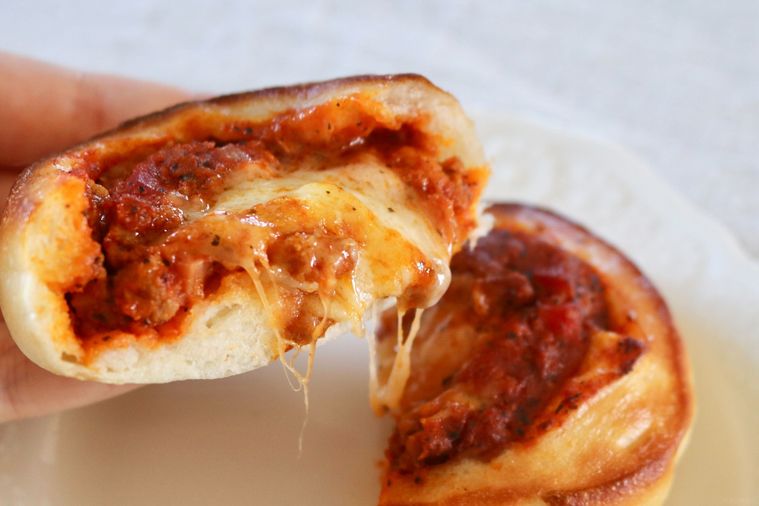 チーズがとけているピザを持ち上げている