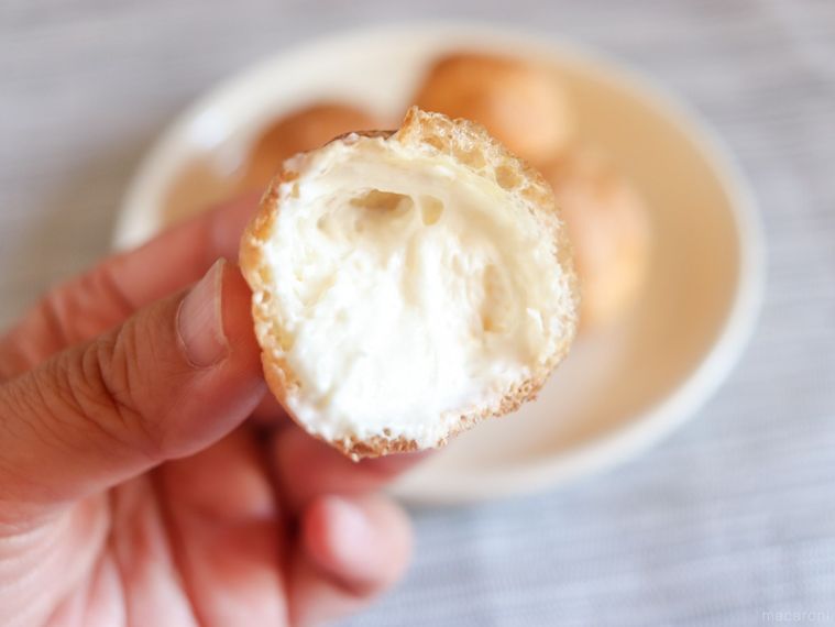 半分に割ったモンテール9Pチーズクリームプチシューを手で持っている様子