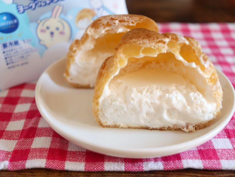 赤いランチョンマットの上に、むちゃうまヨーグルトシュークリームの包装と白いお皿にのせたシュークリームが置かれている