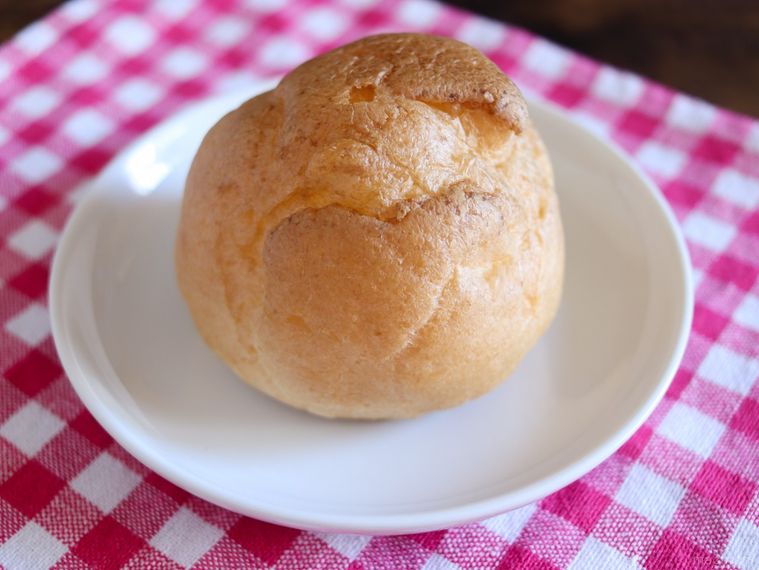 赤いランチョンマットの上に、むちゃうまヨーグルトシュークリームをのせた白いお皿が置かれている