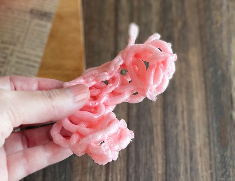 揚げたクルプックを手で持っている写真