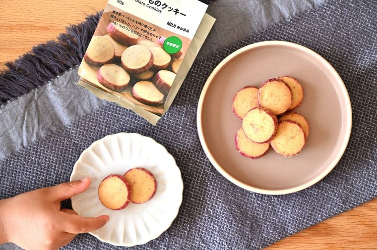 小皿に出したさつまいものクッキーと、クッキーを取ろうとする子どもの手