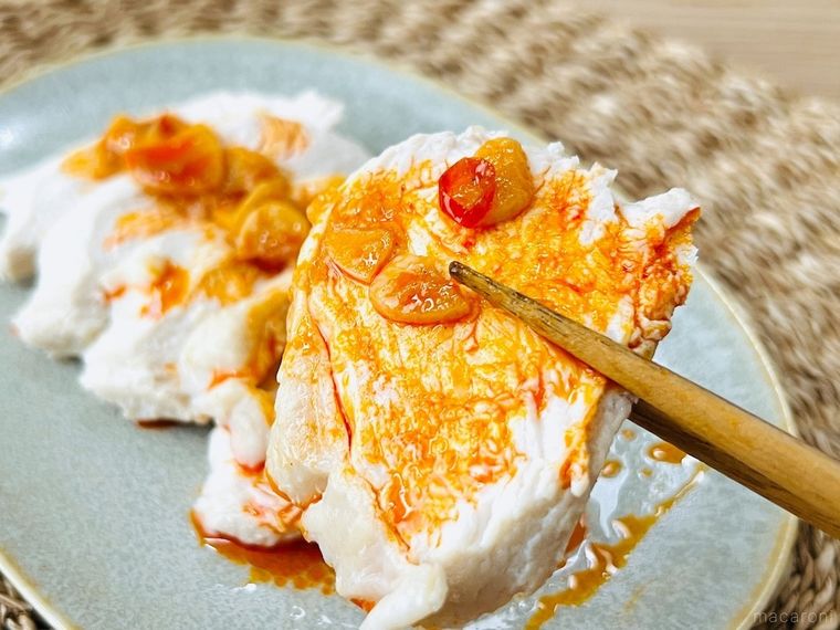 梅にんにく辣油 赤唐辛子がかかった蒸し鶏を箸で持ち上げている様子