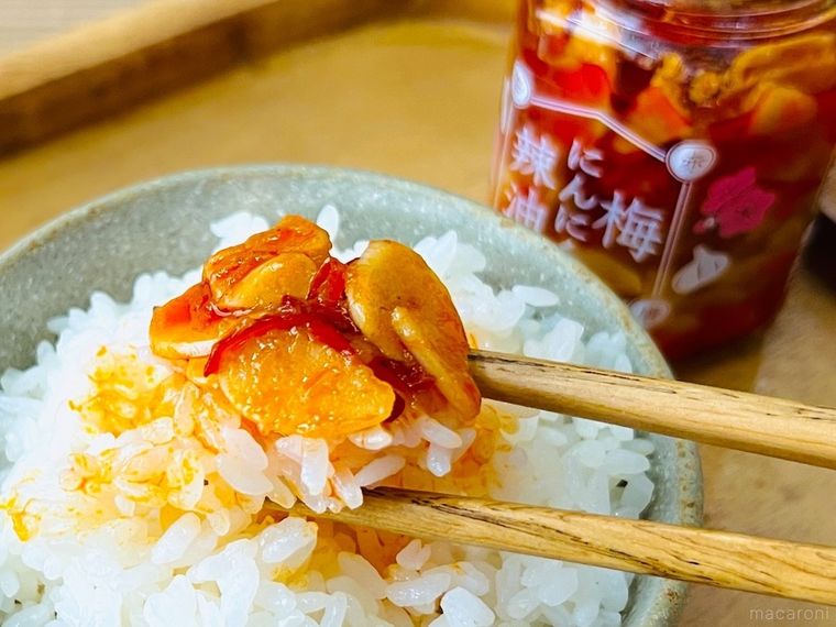 梅にんにく辣油 赤唐辛子がのったごはんを箸ですくっている様子