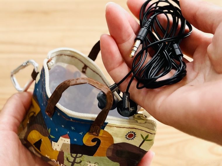 カルディ伝説柄カラビナ付きミニバッグにイヤホンを入れようとしている様子