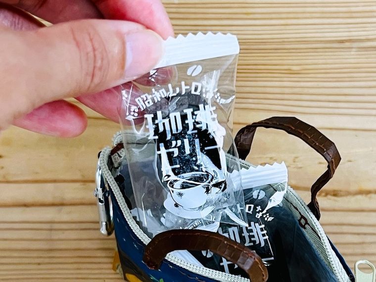 カルディ伝説柄カラビナ付きミニバッグからコーヒーゼリーを取り出している様子