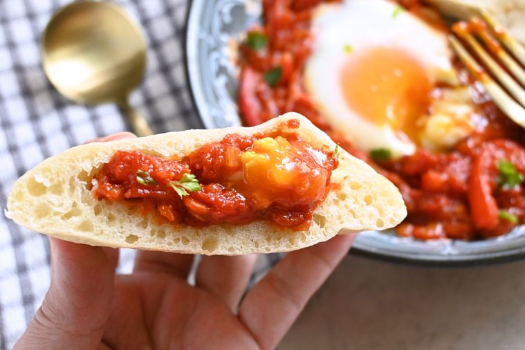 シャクシュカを詰めたピタパンを手に持つ様子