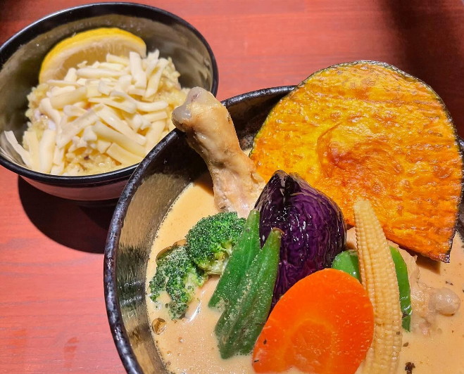 器に盛られたチキン野菜カリーとチーズがのったライス