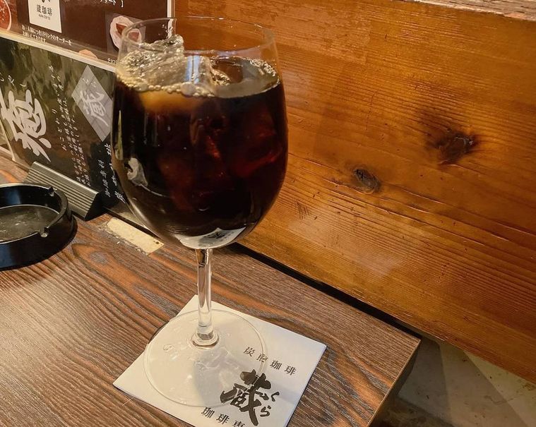 木製カウンターに置かれた氷入りのアイスコーヒー