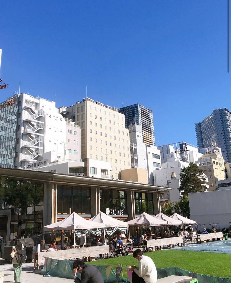 高層ビル群を背景に、青空の下で賑わう屋外カフェのテラス席