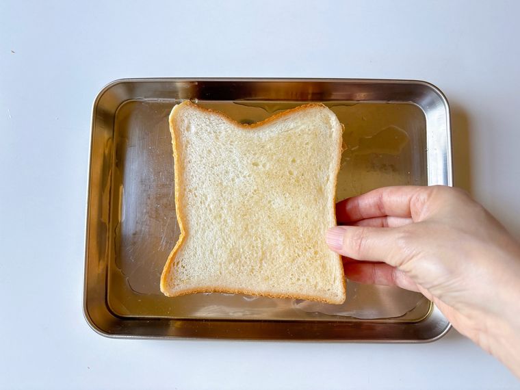 金属トレーに麦茶を入れて食パンに浸す様子