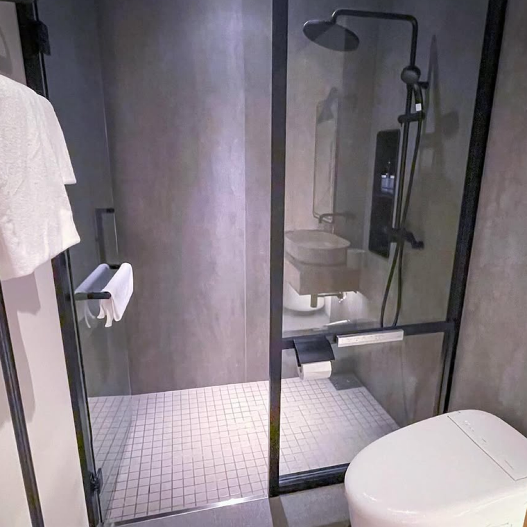 グレーを基調とした壁と、白いタイルが特徴的なシャワールーム