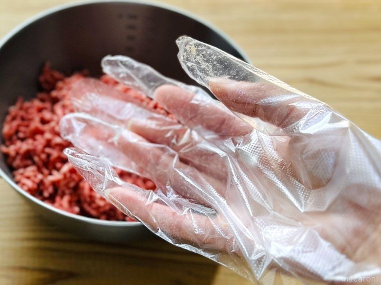 ひき肉が入ったボウルと、使い捨て手袋をはめた手