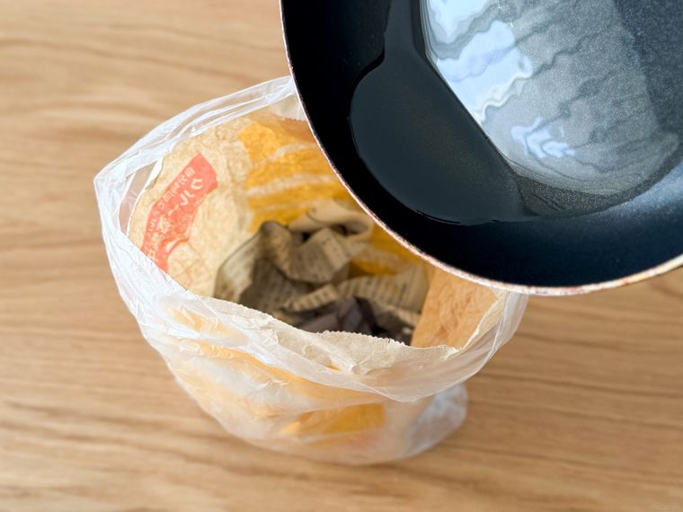 新聞紙を入れたマクドナルドの袋に油を入れようとしている様子