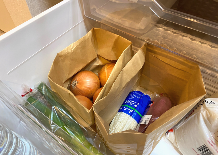 紙袋に入った野菜が野菜室に保管されている