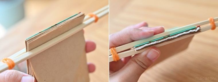 割箸と輪ごむで固定した紙にボンドを塗っている