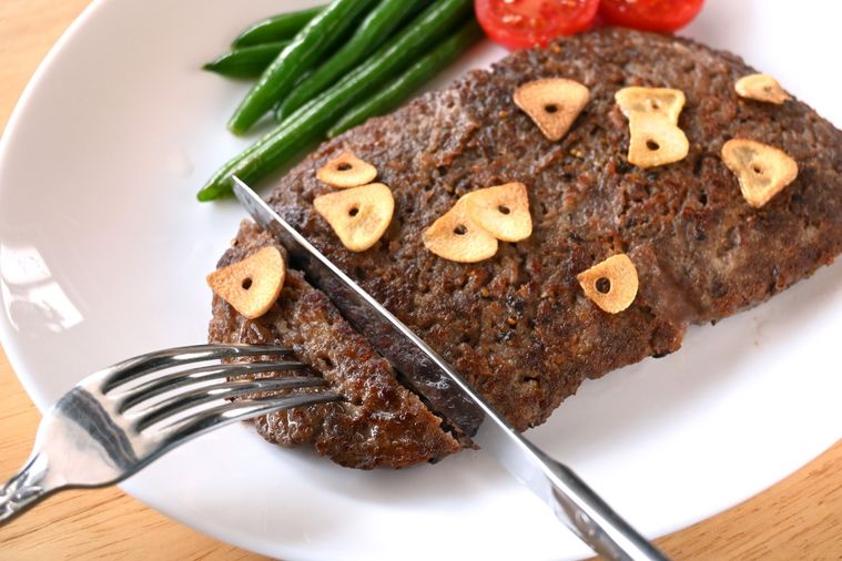 ひき肉ステーキにナイフとフォークを差し入れる様子