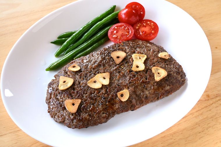 白い楕円形の皿に盛り付けられたひき肉ステーキ