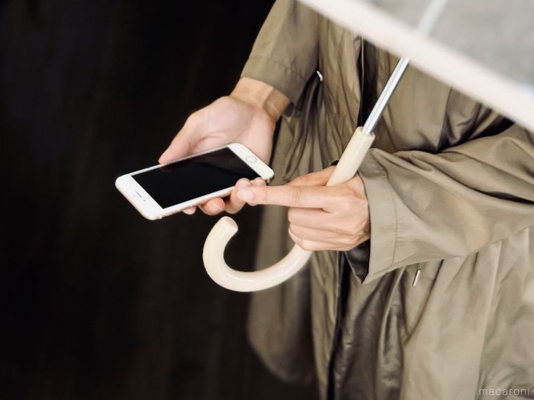 傘をさしながらスマートフォンを操作しようとしている様子