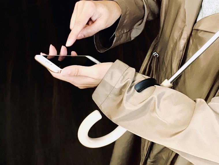 傘をさしながらスマートフォンを操作している様子
