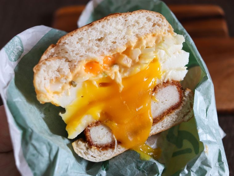 半分にカットしたケンタッキートリプル月見バーガーを手で持っている