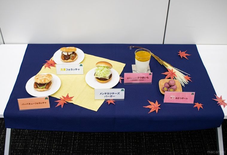 もみじが飾られた青いクロスの上にモスバーガーの月見シリーズ各商品が並んでいる