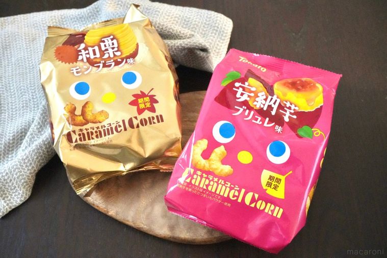 木のカッティングボードにのった安納芋と和栗のコーンスナックの金色とピンク色のパッケージとストライプの布