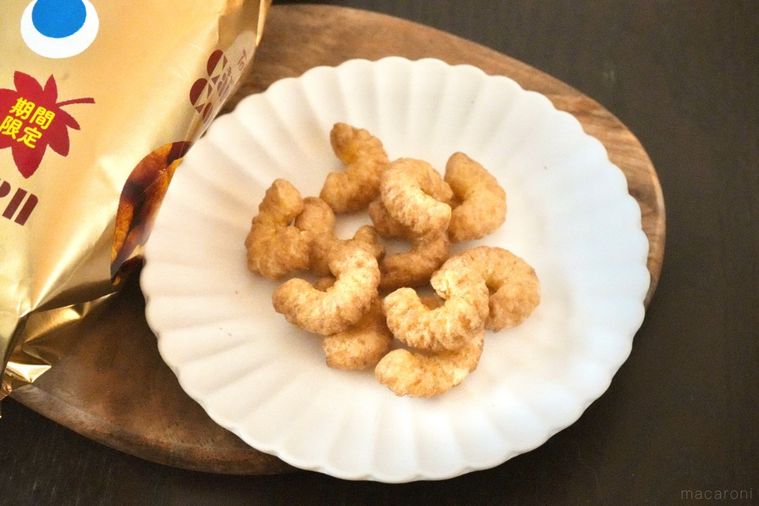 木のカッティングボードと白い皿にのった和栗モンブラン味のコーンスナックと金色のパッケージ