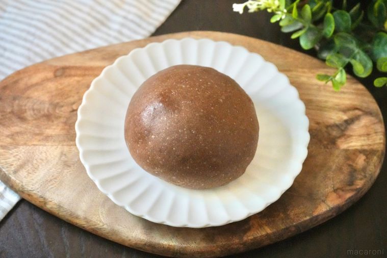 木のカッティングボードと白い皿にのったチョコレート味の丸いクリームパンとストライプの布とグリーン