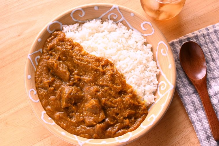 丸皿に盛り付けられたカレーに木製スプーンが添えられている