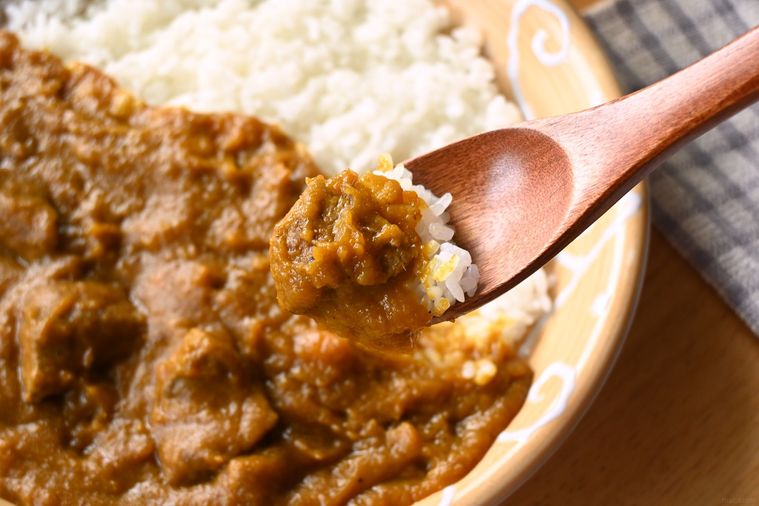玉ねぎなしカレーを木のスプーンですくう様子
