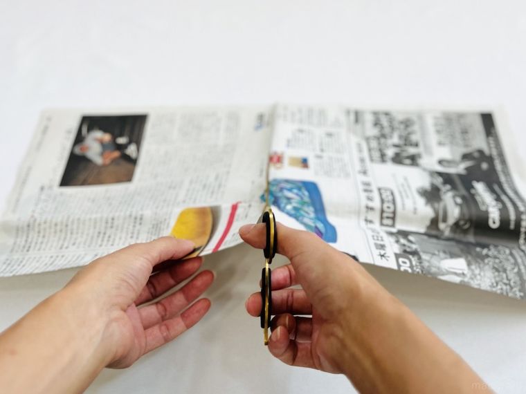新聞紙をハサミで切っている様子