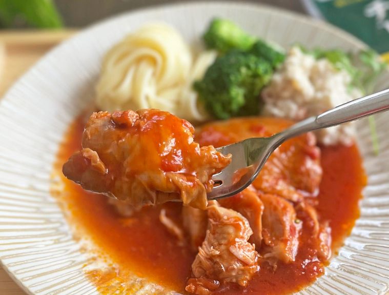 チキンのトマト煮をフォークでひと口分持ち上げているところ