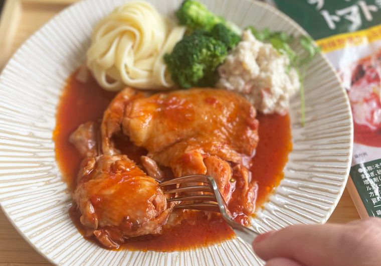 業務スーパーチキンのトマト煮をフォークでカットしている写真