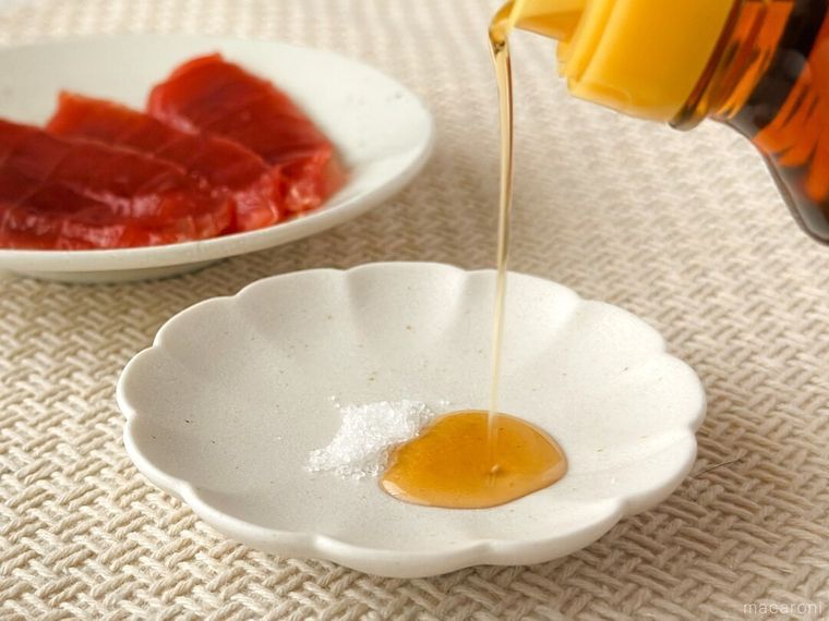 塩が盛り付けられた白皿に金印純正ごま油を注いでいる様子