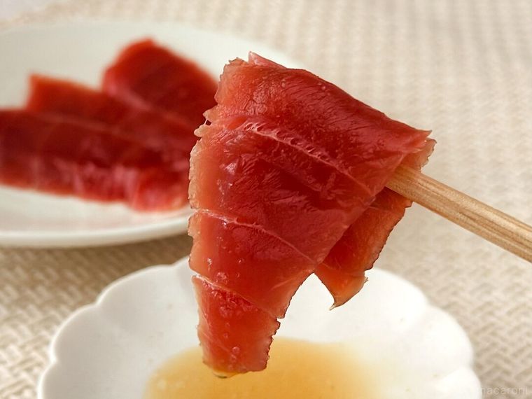 金印純正ごま油と塩をつけたまぐろを箸で持っている様子