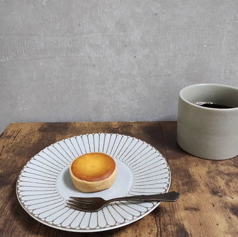 白いお皿に盛られたみかんの花咲く丘とコーヒー