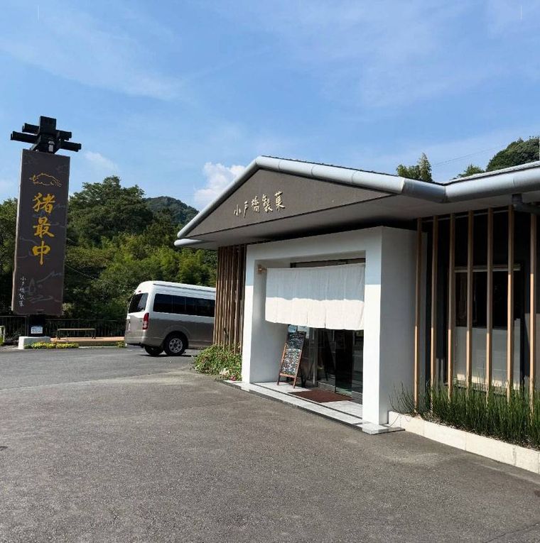 道路沿いに大きな看板が立ち白いのれんがかかった小戸橋製菓 本店の外観