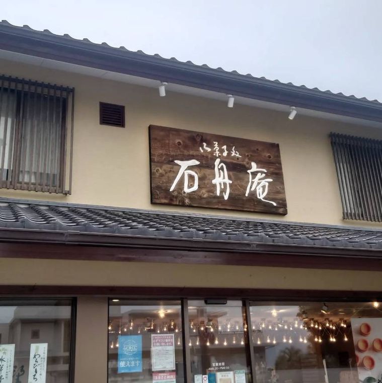 クリーム色の外壁に木の大きな看板がかかった石舟庵 湯川本店の外観