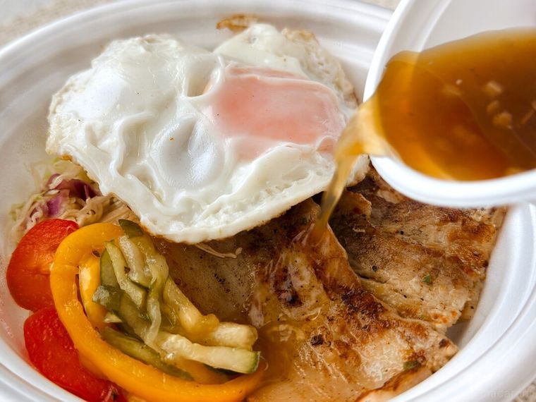 コムタム風ポークライスにヌクマムソースをかけている様子