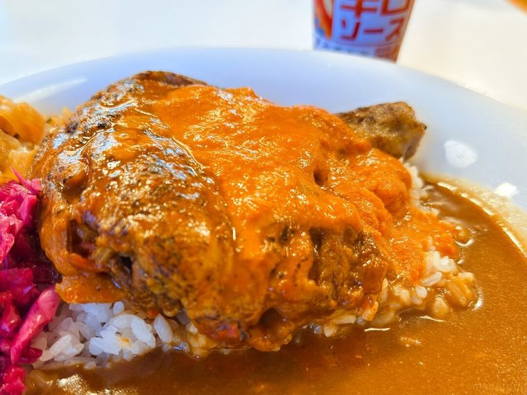 白皿に盛り付けられたバターチキンソースカレーと辛口ソースが並んでいる様子