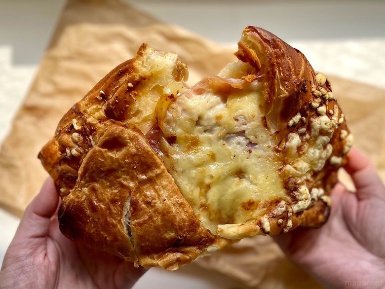 コストコ フードコートのクロワッサンハムチーズを手で半分にちぎっている様子